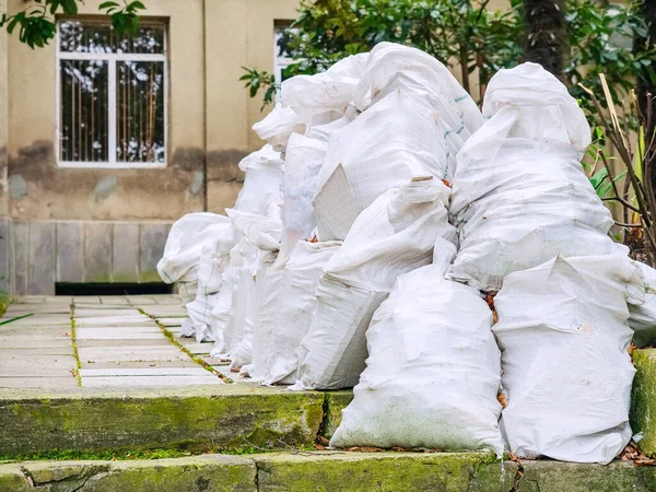 Birbirinin aynısı pek çok çöp torbası evin yakınına yığılmış.