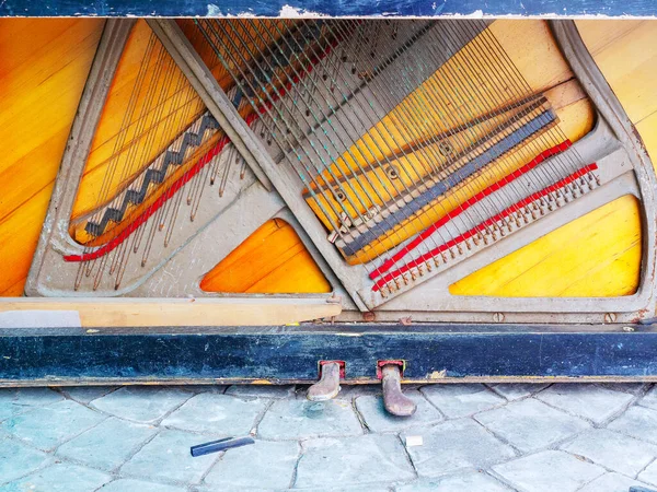 Der Boden eines alten kaputten Klaviers mit Pedalen und nackten Saiten — Stockfoto