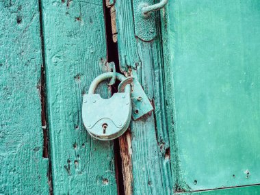 Eski mavi ahşap bir kapıya asılı mavi bir demir kilit. Yakın plan fotoğraf.