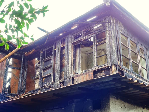 Fragment of a burnt old ruined wooden house with frames without glass — Stock Photo, Image