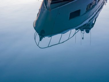 Mavi bir yatın bir parçası sakin deniz suyuna yansıyor.