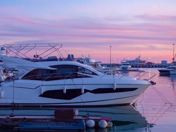 White yacht docked in the harbor against the background of a pink sunset sky reflected in the sea — Stock Photo, Image