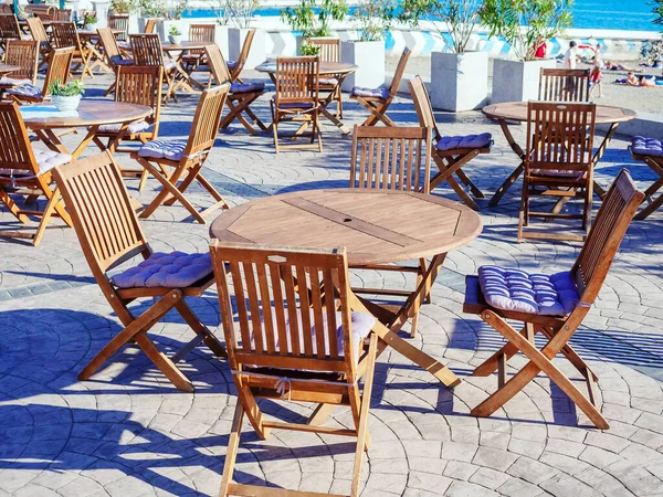 丸みを帯びた木製のテーブルと折りたたみ椅子とストリート海辺のカフェ — ストック写真