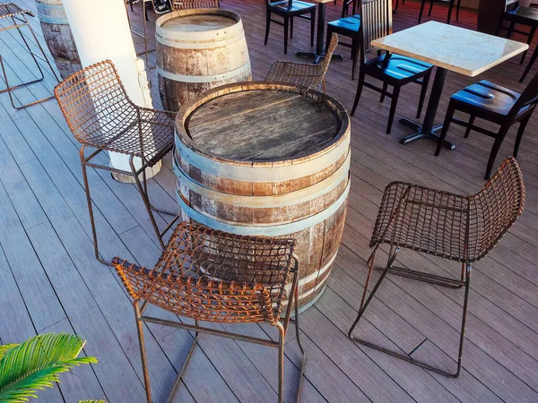 木樽と金属製の椅子で作られたテーブルで、屋外カフェにウィッカー席があります。 — ストック写真
