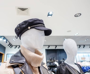 Bir elbise mağazasının arka planında siyah şapkalı bir mankenin yanında soyut bir mankenin başı.