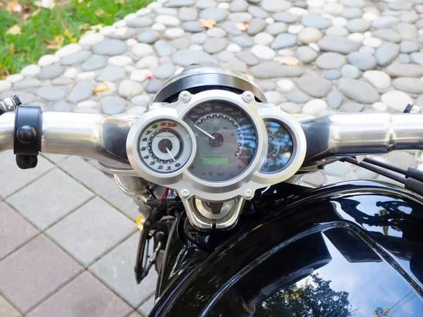 Kierownica motocykla z okrągłym prędkościomierzem na tle płyt chodnikowych i dekoracyjnego muru — Zdjęcie stockowe
