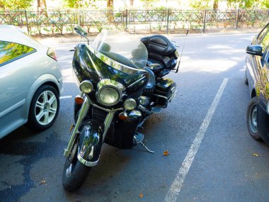 Bir bahar günü arabaların arasına park edilmiş siyah parlak bir motosiklet.