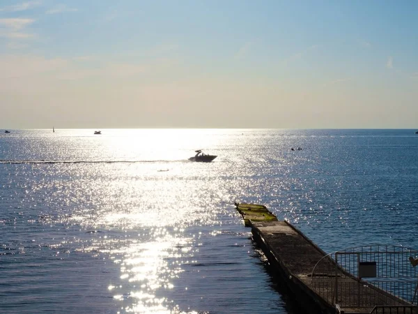 Mar com pontão de sol brilhante e barcos sob o céu azul — Fotografia de Stock