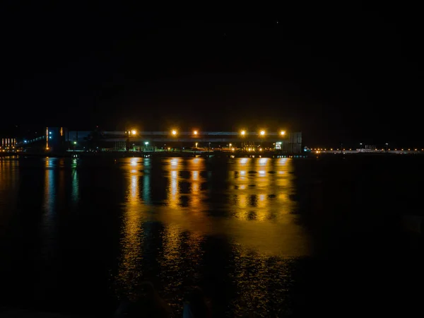 Marina noturna com uma grande estrutura metálica no cais iluminada por luzes brilhantes — Fotografia de Stock