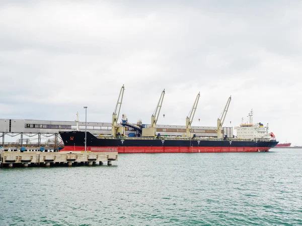 Um navio enorme com guindastes de carga fica no porto — Fotografia de Stock