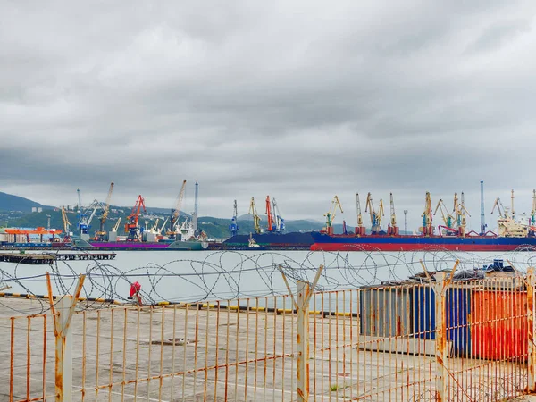 Rússia, Tuapse 15.11.2020. Porto marítimo industrial com grandes balsas e muitos guindastes de carga atrás de uma cerca de arame farpado — Fotografia de Stock