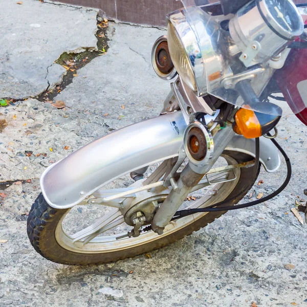 Fragmento de una motocicleta con cables de rueda delantera y faros de pie sobre asfalto agrietado —  Fotos de Stock