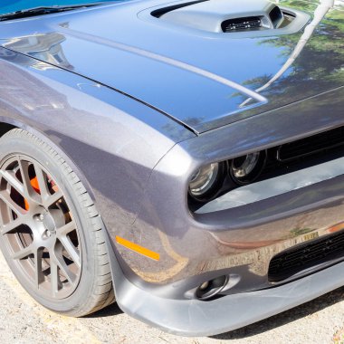 Düşük gri, parlak, tekerleği ve yuvarlak farları olan bir arabanın parçası. Yakın plan fotoğraf.