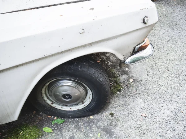Un fragmento de un coche viejo ruso blanco ligeramente escamoso con una rueda negra sobre asfalto áspero —  Fotos de Stock