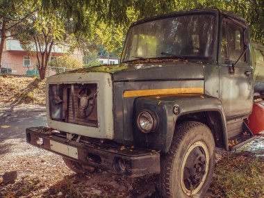 Bir kamyon caddede bir ağacın altında duruyor ve kaputu terk ediyor. Yan görünüm