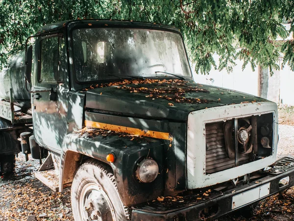 Un camion si trova sulla strada sotto un albero e lascia sul cofano — Foto Stock