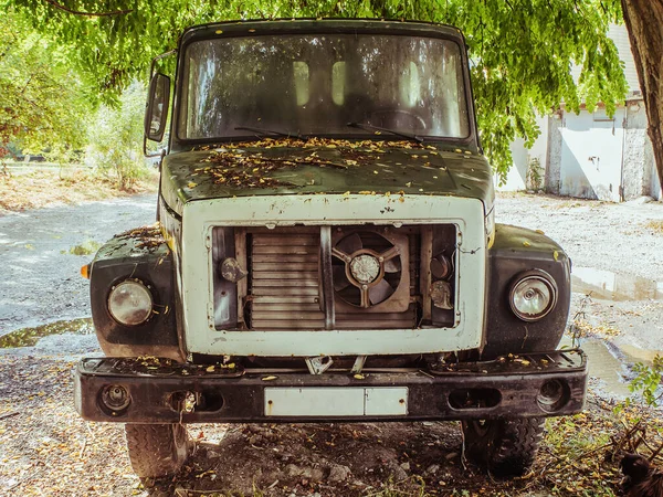 A truck stands on the street under a tree and leaves on the hood. Front view — Stock Photo, Image