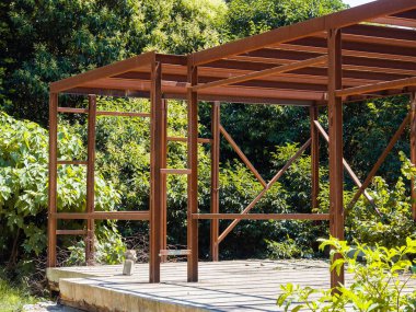 Ağaçların arasında beton bir levhanın üzerinde duran metal bir yapı. Metal iskelet inşaatı