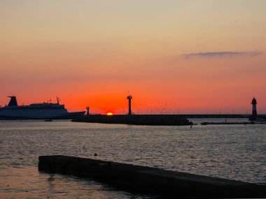Gemi batan güneşin arka planına karşı körfeze giriyor.
