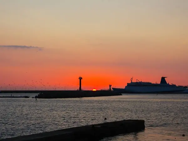 Le navire entre dans la baie de la mer sur fond de soleil couchant et les oiseaux qui tournent autour de la mer — Photo