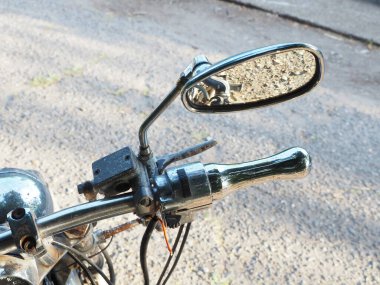 Aynada yansıtıcı asfalt olan paslı motosiklet gidonunda dikiz aynası.