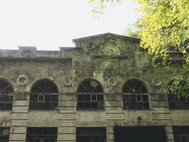 Ahşap çerçevelerde yarı dairesel pencereleri olan terk edilmiş eski bir binanın ön cephesi