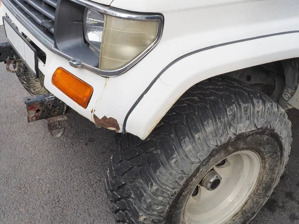 Fragmento de primer plano de coche blanco con pintura astillada en la rueda delantera y sucia —  Fotos de Stock