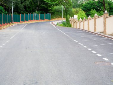 İşaretler, çitler ve yeşil ağaçlarla yeni asfalt döşenmiş.