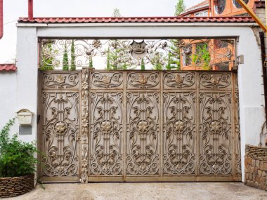 Demir kapılar, gösterişli işlenmiş demir dekorlar çeşitli monogramlarla süslenmiş.