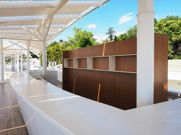 A summer bar with empty shelves and a white bar is located under a white canopy against a backdrop of green trees and palms