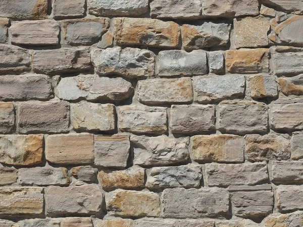 Rough masonry wall with broken and cracked parts illuminated by sunlight. Closeup photo. Not seamless texture