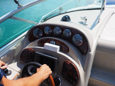 Rusya, Sochi 20.07.2020. Güneş tarafından aydınlatılan yolcu yatının ön panelinde direksiyon tutan erkek el turkuaz denizle denize açılıyor.