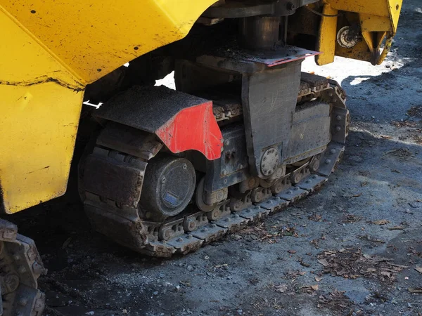 Fragmento de una excavadora con una rueda de orugas llena de camino sin paladar. Oruga en una pavimentadora. —  Fotos de Stock