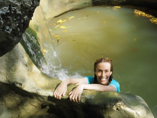 Χαμογελαστό κορίτσι λούζεται σε λασπώδη πισίνα βραχώδη φαράγγι κοντά διαφανή χείμαρρο καταρράκτη — Φωτογραφία Αρχείου