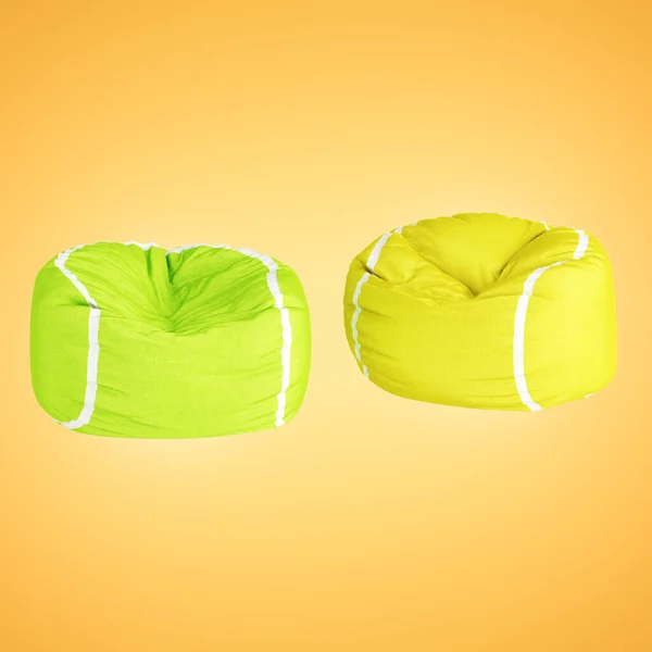 Dos bolsas de sillón de tela suave con colores de pelota de tenis sobre un fondo naranja retroiluminado. renderizado 3d —  Fotos de Stock