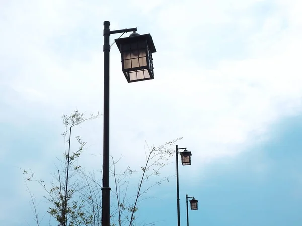 Pillars with decorative street lamps stand in a row against a sky with a cloudy haze — Stock Photo, Image