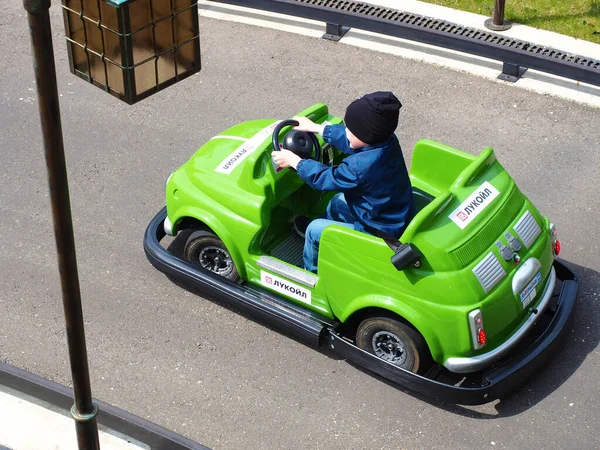 Russia, Sochi 16.04.2021. Un ragazzo guida una macchina verde in miniatura con l'iscrizione lukoil sulla pista di kart per bambini — Foto Stock