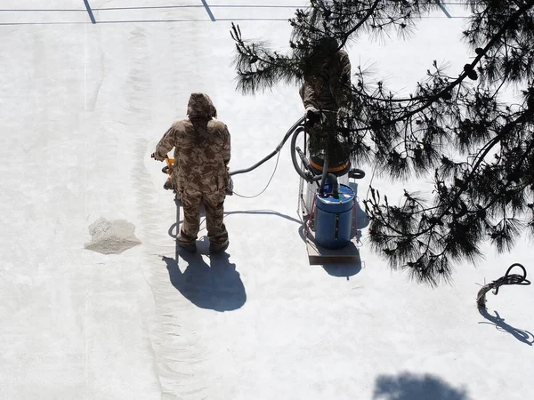 Tulumlu işçiler, endüstriyel elektrikli süpürgeyle güneşli bir alanda beton kaldırımdan inşaat tozu çıkarıyorlar. Sokak yenileme — Stok fotoğraf