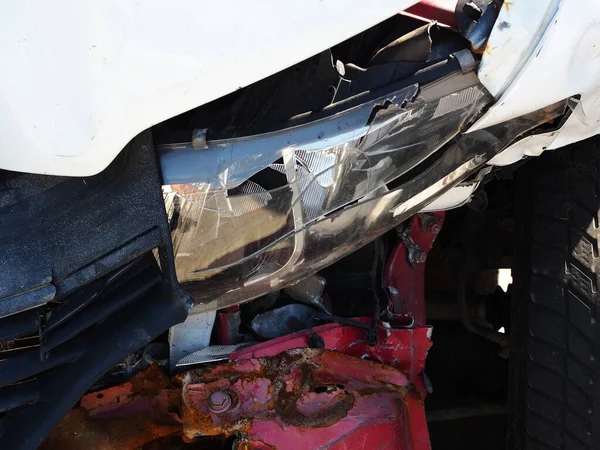 A fragment of a car with a broken headlight and a dented rusty bumper. Car after an accident. Closeup photo —  Fotos de Stock