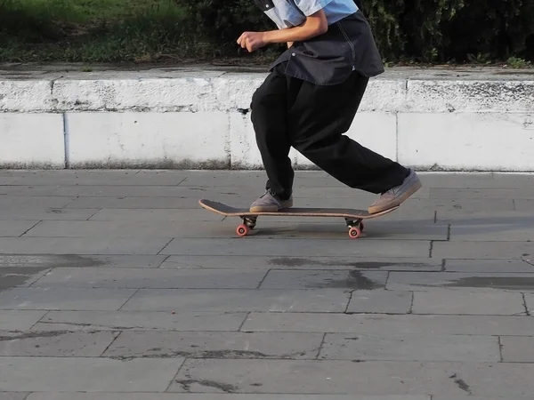 Teenager cavalca uno skateboard accovacciato su un'area piastrellata di granito — Foto Stock