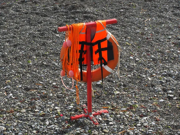 Lifebuoy і lifejacket висять на металевій підставці на гальковому пляжі — стокове фото