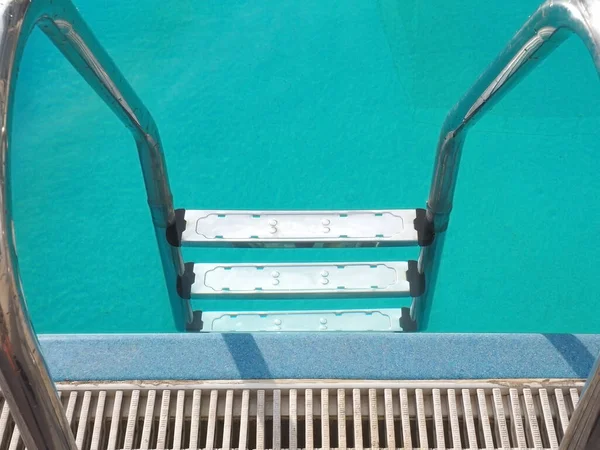 Escadaria de metal prateado com grades cromadas que levam à piscina azul-turquesa — Fotografia de Stock