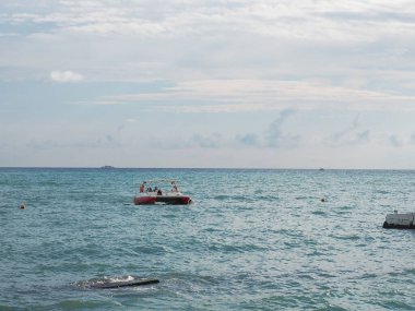 Turistli tekne gökyüzünün altındaki deniz dalgalarında yüzüyor.