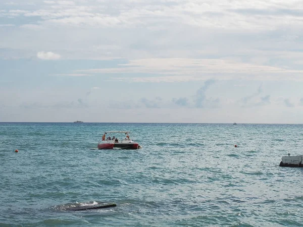 O barco com turistas flutua nas ondas do mar sob o céu com nuvens — Fotografia de Stock