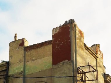 Duvarları soyulmuş ve gökyüzüne karşı çatısı olmayan eski bir binanın tepesinde.