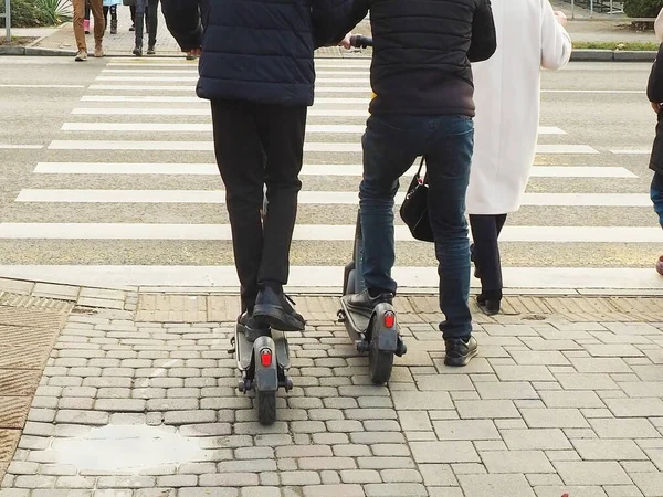 Les adolescents sur des scooters traversent la route le long d'un passage pour piétons entre autres personnes — Photo