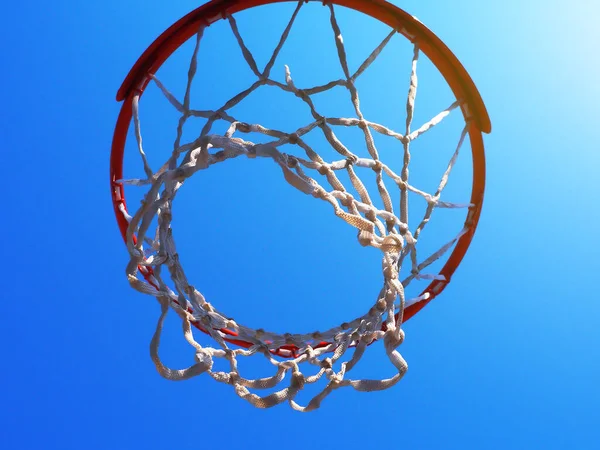 Aro de baloncesto con una red contra un cielo azul sin nubes bajo los rayos del sol. Foto de primer plano de abajo hacia arriba —  Fotos de Stock