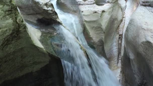 Wąski wodospad przepływający przez płaskie białe skały. Widok z bliska — Wideo stockowe