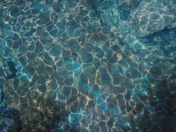 A pond with bright iridescent water and a rocky bottom. Full screen photo