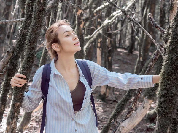 Una ragazza che si fa strada attraverso un boschetto di una fitta foresta ricoperta di muschio in un giorno d'estate — Foto Stock